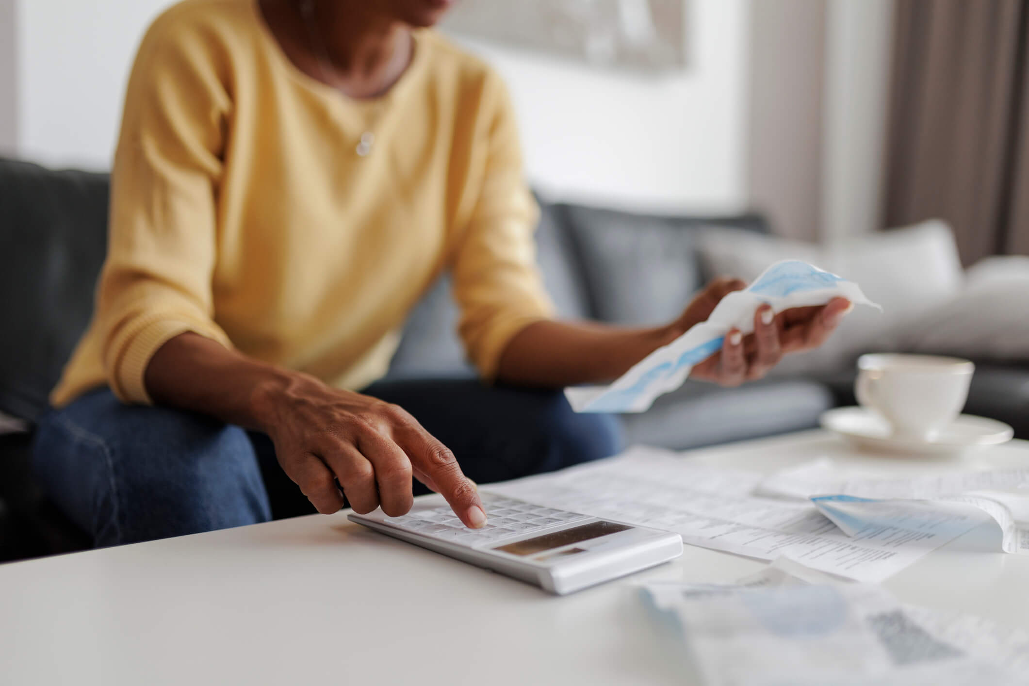 Person calculating household bills with calculator