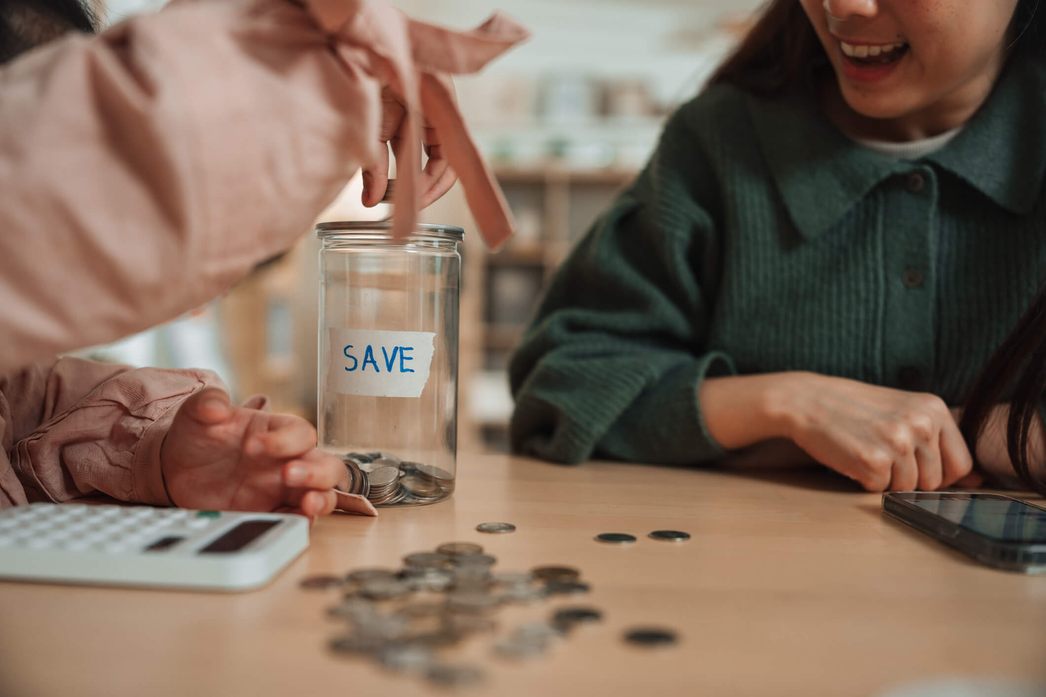 Hands placing coins into jar labeled "SAVE