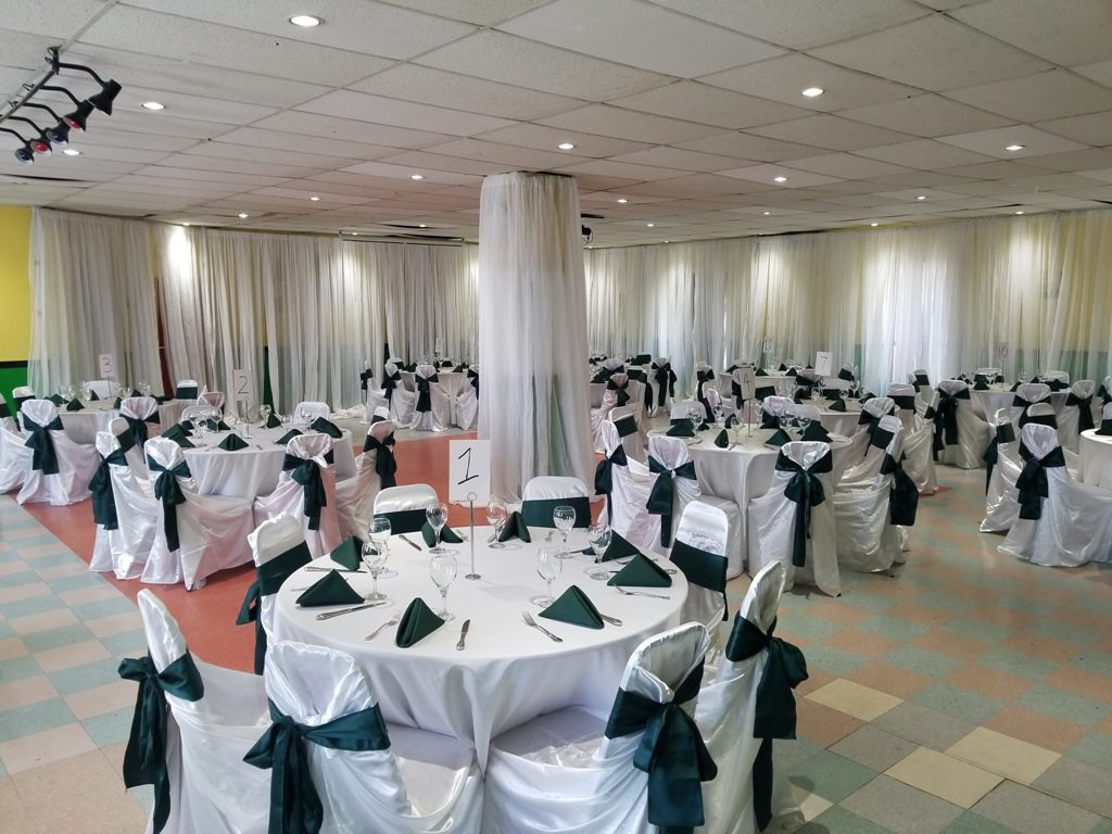 Elegant banquet hall with white chairs, green accents